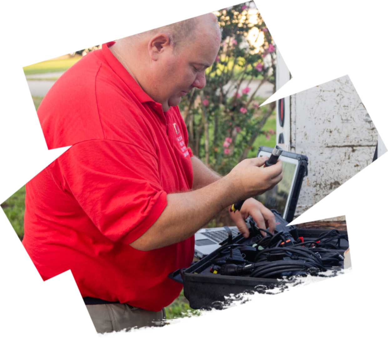 A man in red shirt using laptop outside.